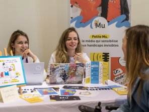 URRH 2023 - Photo du stand "La petite Mu". Echange entre un participant et les fondatrices de "Petite Mu", Alice Deves et Anaëlle Marzelière.